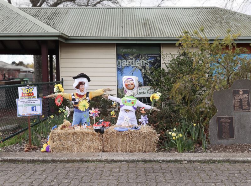 Two scarecrows dressed as Woody and Buzz Lightyear on hay bales